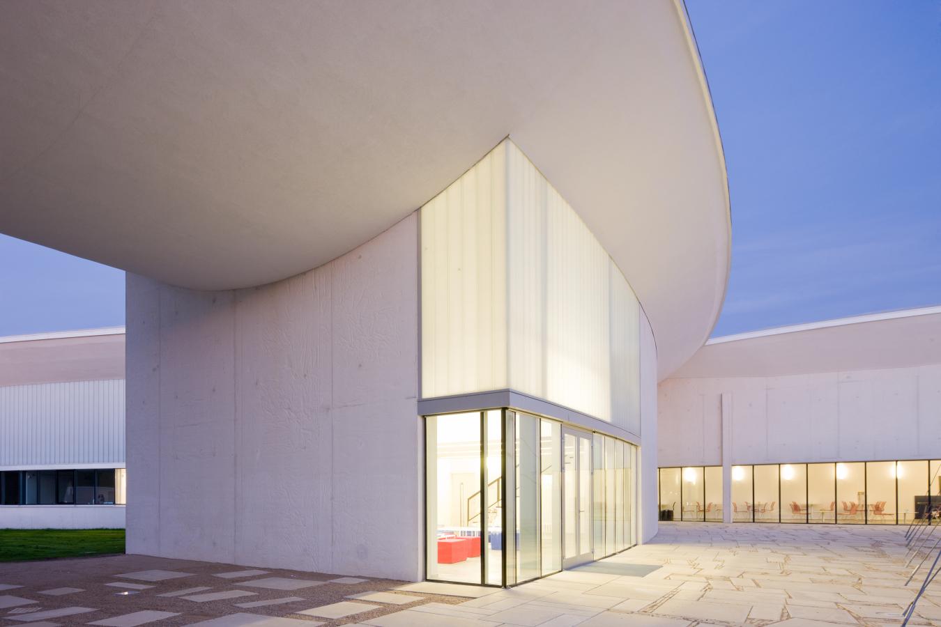 Et kunstmuseum i Herning som har lys i vinduerne om aftenen