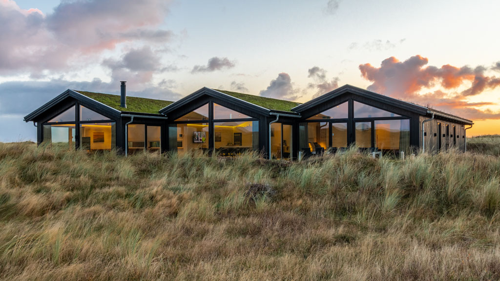 Tre sorte feriehuse med solnedgang i baggrunden